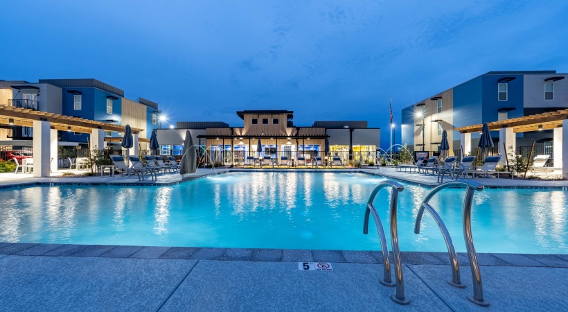 FLATZ 520 pool at dusk shows modern buildings with exterior lighting, pool stairs, large windows, and balconies.