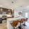Luxury kitchen at FLATZ 520 features dark cabinets, stainless appliances, island with stools, and adjacent living area.