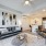FLATZ 520 open-concept living has dark sofa, abstract art, armchair, kitchen with bar counter, and stainless appliances.
