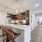 Spacious kitchen at FLATZ 520 has dark cabinets, stainless appliances, island with stools, flowers, and hallway view.