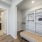 Walk-in closet at FLATZ 520 includes shelves, boxes, bench, adjacent bathroom with sink and mirror, wood floor, and white walls.