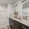 Luxury bathroom at FLATZ 520 has tub, green curtain, double sinks, black cabinets, mirrors, and decorative items.
